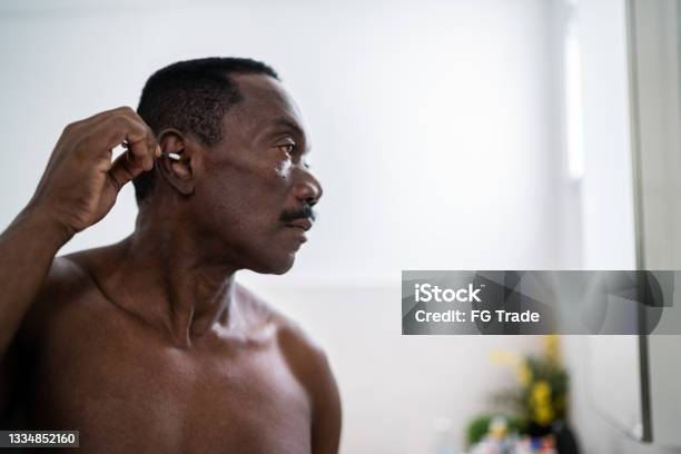 Senior Man Cleaning His Ear With A Cotton Swab At Home Stock Photo - Download Image Now