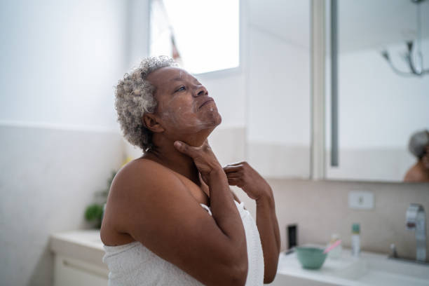 senior woman applying body moisture in the bathroom at home - joint bathroom stok fotoğraflar ve resimler