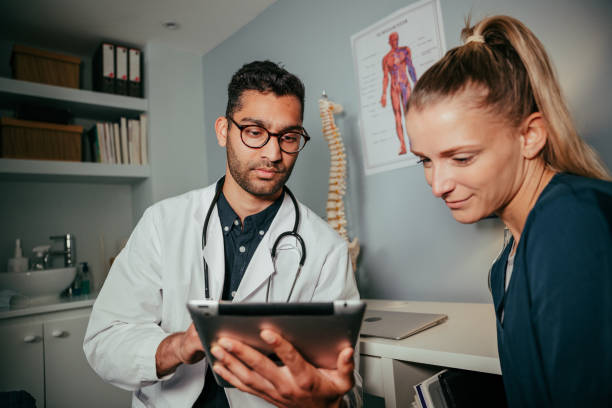 istock mixed race female nurse sitting with male doctor using digital tablet 1334852957