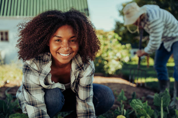 菜園組織で働く美しい笑顔の女性農家は、アクティブな感じを生産します - africa farmer african descent agriculture ストックフォトと画像
