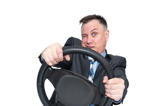 Emotional man in a dark jacket is reckless on the road while making a turn while holding a car steering wheel. Isolated on white background.
