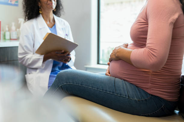 Unrecognizable pregnant woman and female doctor have discussion during appointment stock photo