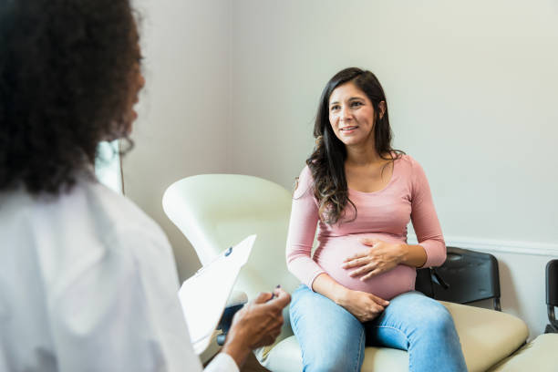 kobieta w ciąży opiera rękę na brzuchu, słuchając lekarza - human pregnancy midwife visit healthcare and medicine zdjęcia i obrazy z banku zdjęć