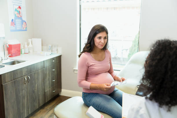 female patient and unrecognizable female doctor discuss pregnancy issues - human pregnancy midwife healthcare and medicine visit imagens e fotografias de stock