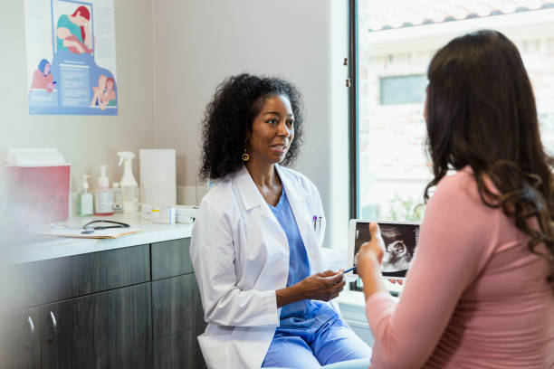Doctor and patient discuss ultrasound during appointment A mature adult female doctor and an unrecognizable pregnant woman discuss an ultrasound during an appointment. midwife photos stock pictures, royalty-free photos & images