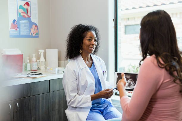 doctor and patient discuss ultrasound during appointment - human pregnancy midwife healthcare and medicine visit imagens e fotografias de stock