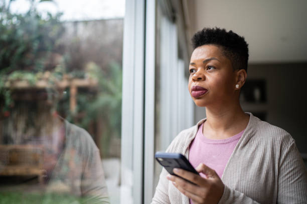 frau, die darüber nachdenkt, das smartphone zu hause zu benutzen - mobile phone telephone frustration women stock-fotos und bilder