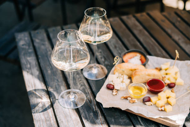 istock A wooden table in a restaurant with a cheese plate, grape, honey bread and white wine. Wine glasses and cheese served for a party in a bar or a restaurant on terrace at a sunny day 1334859529