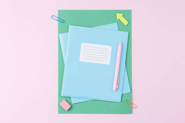 istock Notebook with school supplies on pink background 1334862348
