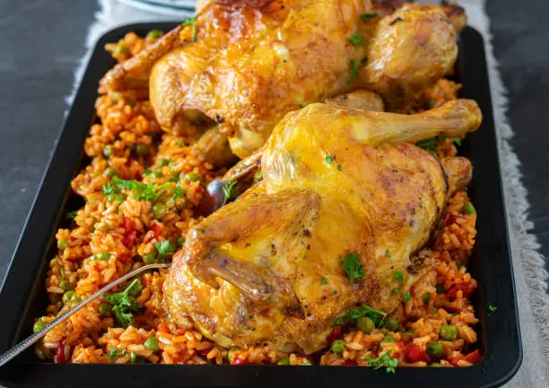 Delicious spicy roasted chicken dish with mediterranean djuvec rice served isolted on a tray on kitchen table background