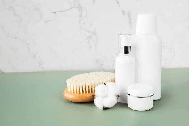 istock Empty white cosmetic containers, jars and body brush sit on the bathroom shelf. A set of cosmetics for face and body care. Copy space. 1334864719