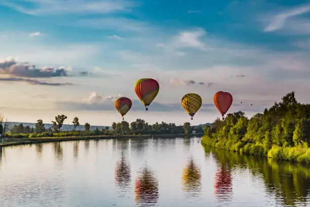 balloons are reflected in the river with blue sky, balloons and sunset