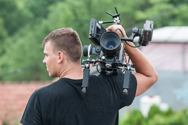 istock Behind the scene. Cameraman with his camera on outdoor set 1334871412
