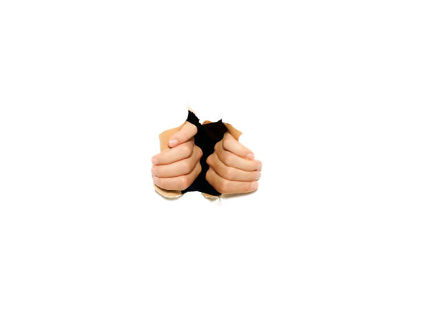 istock Two hands tearing through a white paper wall. Illustrating escaping or breaking into something. 1334872518