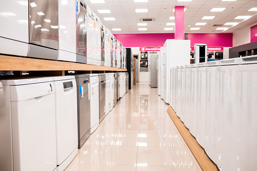 Dishwashing machines and refrigerators seen in  a row just before the opening of a home appliances store for house goods shopping.