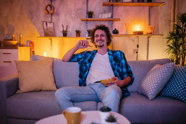 Photo of Man watching movie and eating potato chips