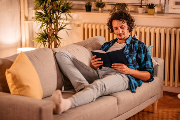 istock Man At Home Lying on sofa and reading book 1334882950
