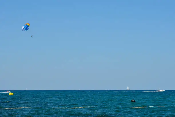 A parascender, or parasailer, and a speed boat off the Adriatic Sea coastline in July north of Novigrad, Istria, Croatia"n