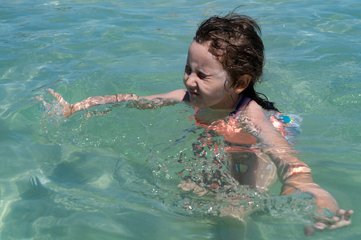Happy laughing toddler girl having fun on in the sea