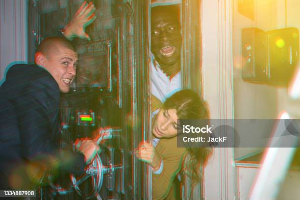 Friends Trying To Open Door In Industrial Quest Stock Photo - Download Image Now - 25-29 Years, 30-34 Years, 40-44 Years