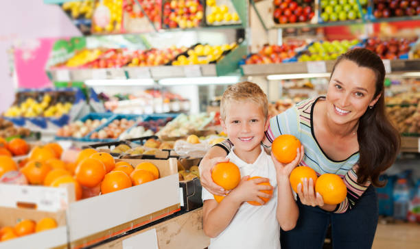 istock mother with little boy buying oranges at store 1334888873