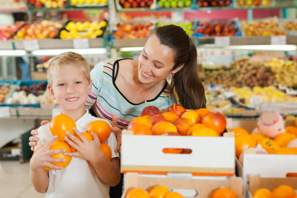 istock mother with little boy buying oranges at store 1334888875