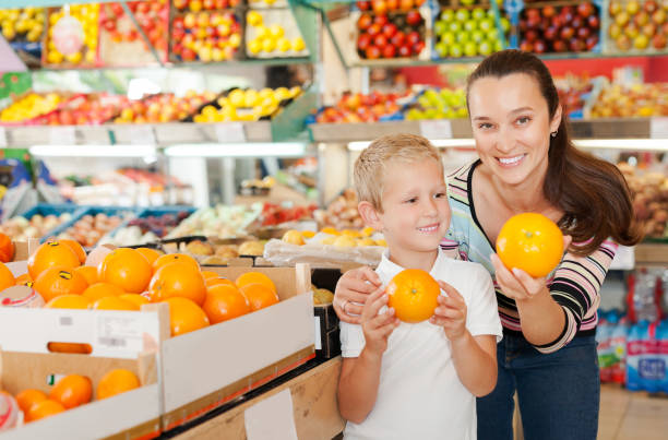 istock mother with little boy buying oranges at store 1334888886