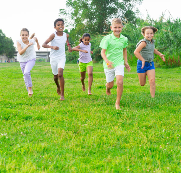 Group of children having fun together outdoors running Group of laughing children having fun together outdoors running child 10 11 years 8 9 years cheerful stock pictures, royalty-free photos & images