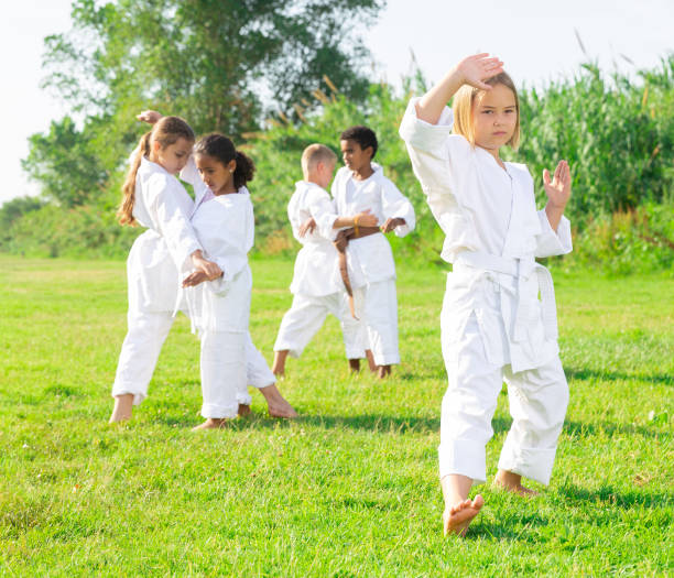 istock Preteen girl practicing karate with group in summer park 1334889074