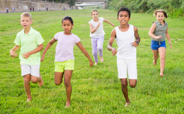 istock Five smiling kids running and laughing in park 1334889142