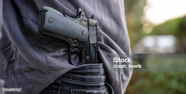 Gloved Hand Carrying A Pistol In His Pants Blur Nature Background Stock Photo - Download Image Now