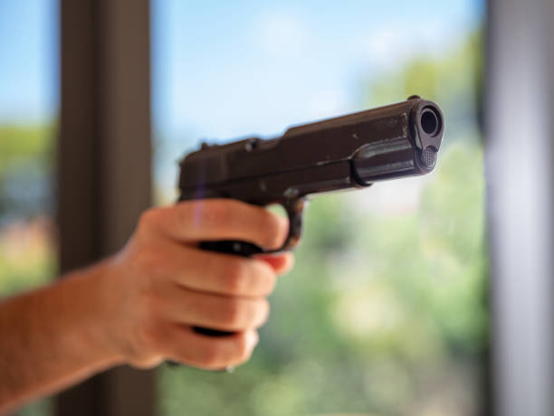 istock Male hand holding a pistol, blur nature background, 1334890773