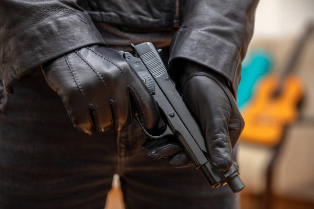 istock Man in a leather jacket holding a pistol closeup view 1334890785