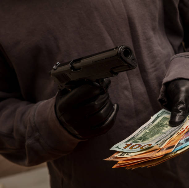 istock Gloved hand holding a pistol stealing money, closeup view. Armed robbery concept 1334890794