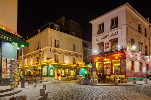 Man sits on the patio of a cafe-restaurant in Montmartre district, Paris, France at night.
