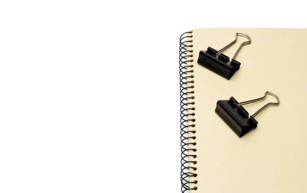 istock Two black metal binder paper clips on a notebook with white space 1334891560