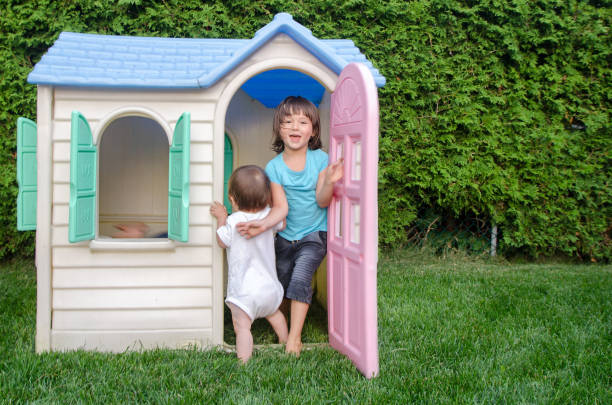 Two mixed race children playing in toy house in backyard Two mixed race children playing in toy house in backyard during day of summer playhouse stock pictures, royalty-free photos & images