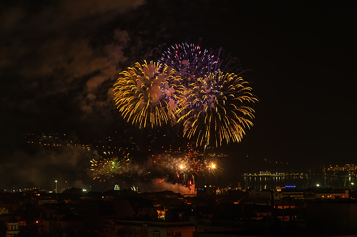 Bright fireworks in the night sky over seashore city and sea. Varna celebrates the city day with colorful fireworks. Night outdoors scene. loud of firework smoke in the dark sky. Real life.