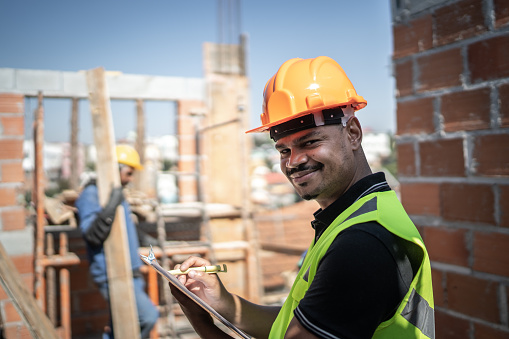 Retrato de un trabajador de la construcción sosteniendo un portapapeles trabajando en una obra de construcción photo
