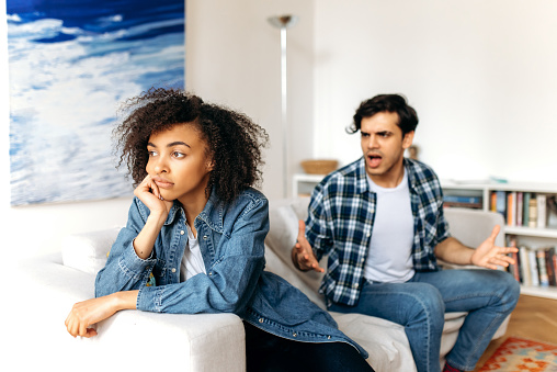 Quarrel, disagreement between a multiracial young couple. Annoyed dissenting guy and girl emotionally sort out the relationship, the guy yells at the girl, the girl resentful turned away from him