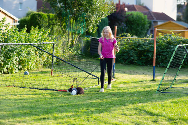 Blond girl, 11 years old, wearing a pink shirt, walking her rabbit, which is black and white, the rabbit is supposed to get some more space, nd the girl is following  the bunny
