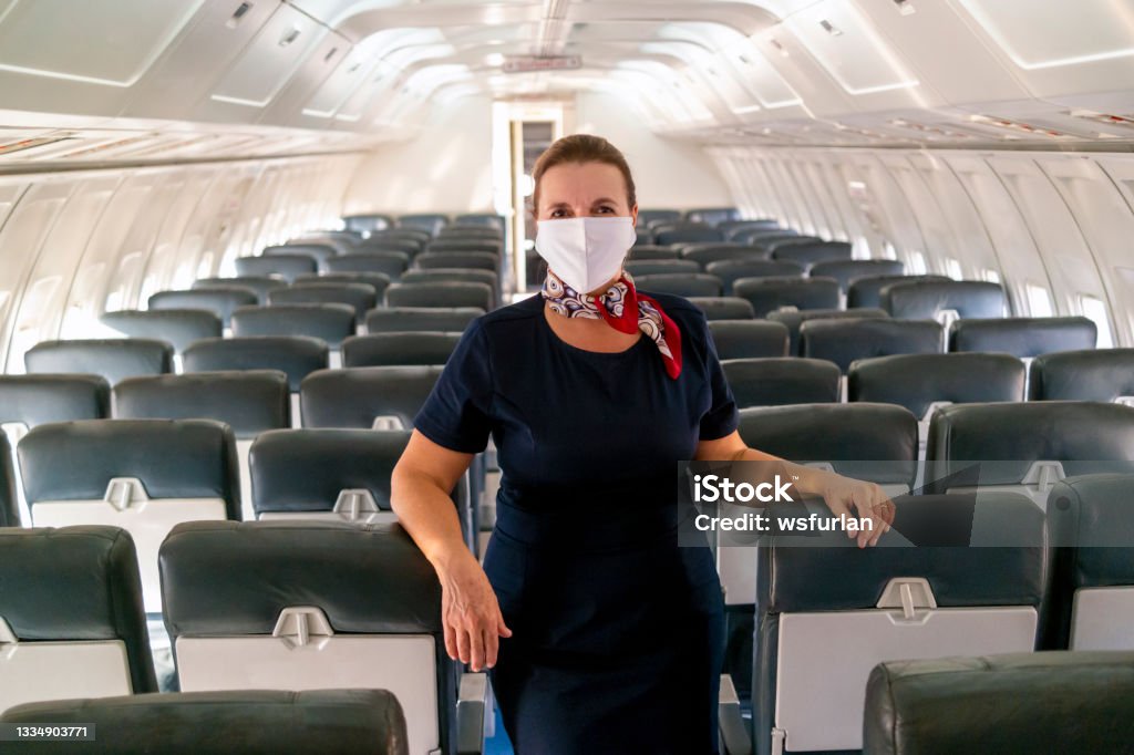 Flight attendant inside an aircraft. Photo of a flight attendant inside an aircraft. Protective Face Mask Stock Photo
