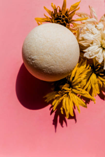 istock Bath bomb with a rough texture on a background of buds. Pink background. 1334906059
