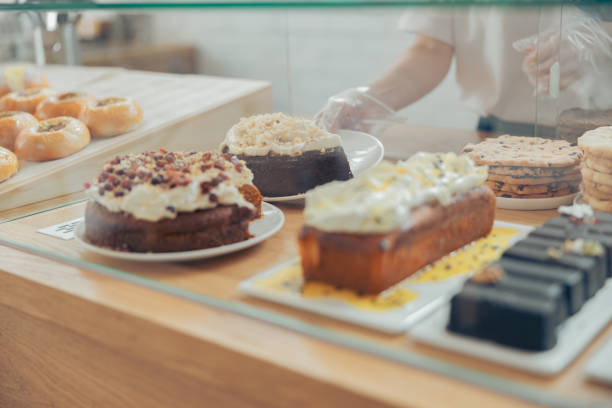 istock Young woman placing cakes on display showcase 1334910672
