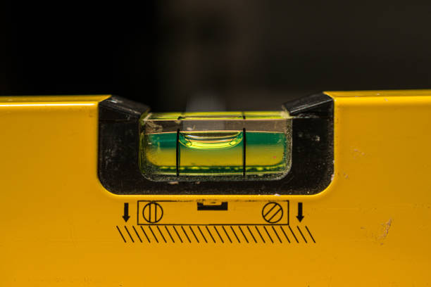 A macro photo of the sprit level on a sprit level ruler where you can see the tool has being used in many jobs with slightly broken plastic holder and its use logo below on the yellow body.