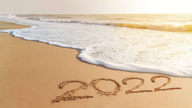 2022 feliz ano novo chegando conceito. ondas brancas estão batendo em direção à costa - passenger ship sunset summer sun - fotografias e filmes do acervo