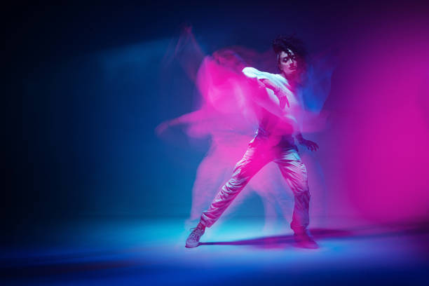 bailando chica de raza mixta en colorida luz de estudio de neón. la bailarina muestra una expresiva danza hip hop. larga exposición - arco iris fotos fotografías e imágenes de stock