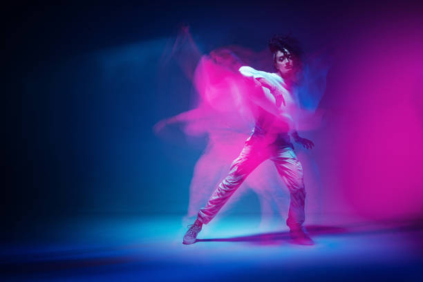 Dancing mixed race girl in colourful neon studio light. Female dancer show expressive hip hop dance. Long exposure Dancing mixed race girl in colourful neon studio light. Female dancer performer show expressive hip hop dance. Long exposure. High quality photo rhythm photos stock pictures, royalty-free photos & images