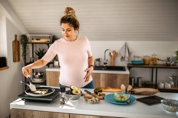 Pregnant woman preparing eggs for breakfast