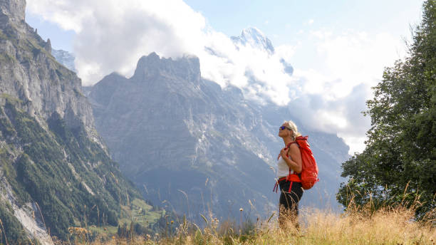 istock Female hiker relaxes on grassy mountain ridge 1334919452